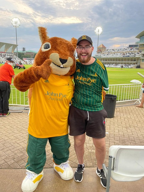 Matthew standing with a mascott at a football match